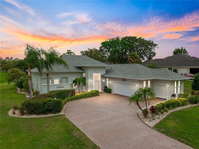 39145 Treeline Dr, Lady Lake, FL 32159 - view of front of house with a garage, stucco siding, decorative driveway, a lawn, and roof with shingles