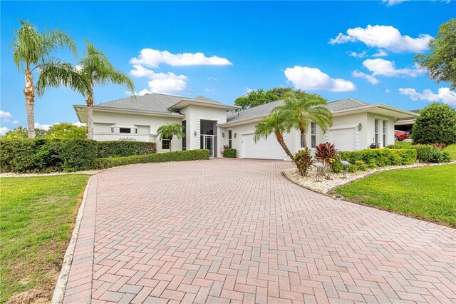 39145 Treeline Dr, Lady Lake, FL 32159 - view of front of property with stucco siding, a garage, decorative driveway, and a front lawn