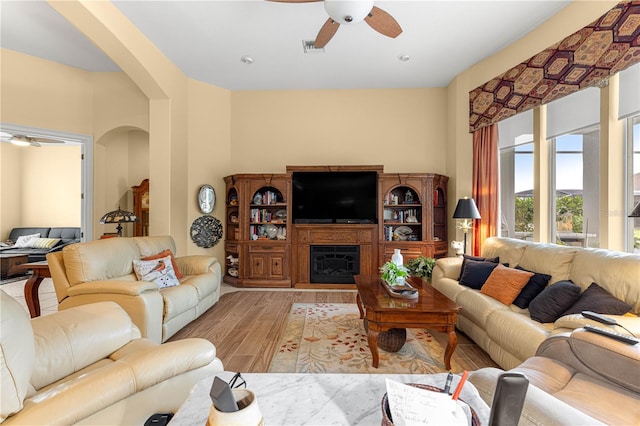 39145 Treeline Dr, Lady Lake, FL 32159 - living area featuring a ceiling fan, arched walkways, wood finished floors, and a fireplace with raised hearth