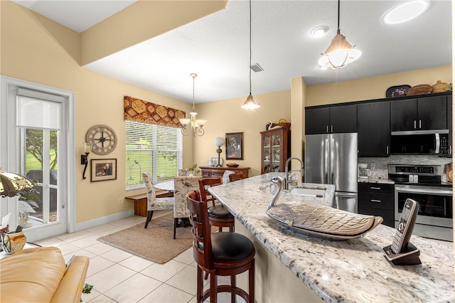 39145 Treeline Dr, Lady Lake, FL 32159 - kitchen featuring appliances with stainless steel finishes, dark cabinetry, a sink, a chandelier, and a kitchen breakfast bar