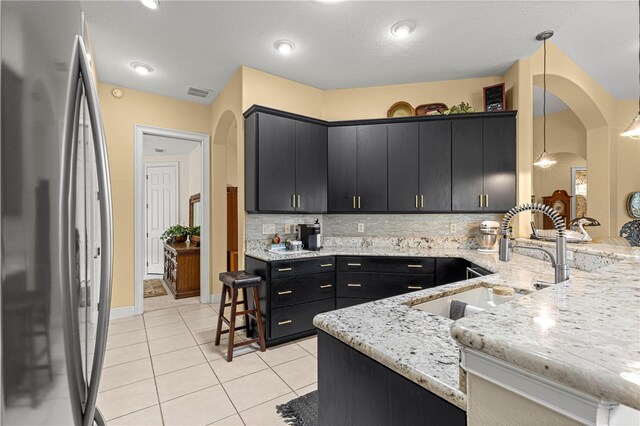 39145 Treeline Dr, Lady Lake, FL 32159 - kitchen with freestanding refrigerator, dark cabinetry, a sink, backsplash, and decorative light fixtures