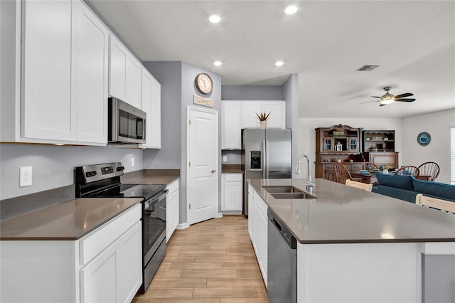 733 Citrus Reserve Blvd, Davenport, FL 33837 - kitchen featuring appliances with stainless steel finishes, a sink, light wood-style flooring, open floor plan, and white cabinets