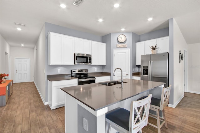733 Citrus Reserve Blvd, Davenport, FL 33837 - kitchen featuring stainless steel appliances, a sink, dark countertops, light wood-style flooring, and a kitchen breakfast bar