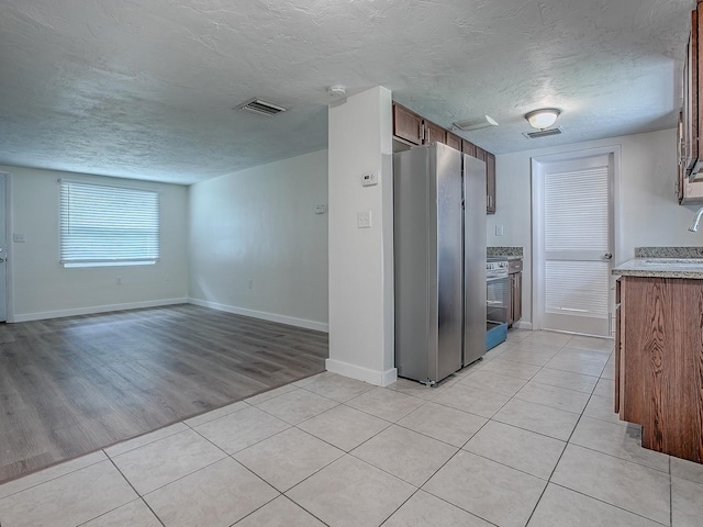 59 S Columbus St, Beverly Hills, FL 34465 - kitchen with freestanding refrigerator, a textured ceiling, light countertops, light tile patterned flooring, and baseboards