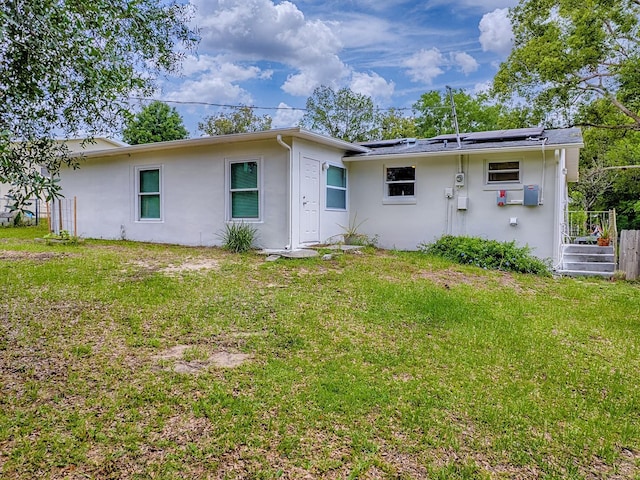 59 S Columbus St, Beverly Hills, FL 34465 - back of house with stucco siding, roof mounted solar panels, and a lawn