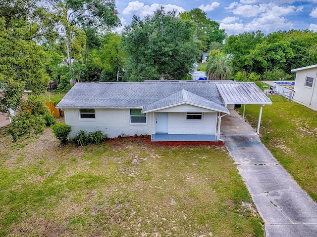 59 S Columbus St, Beverly Hills, FL 34465 - view of front facade with roof with shingles, driveway, brick siding, an attached carport, and view of wooded area