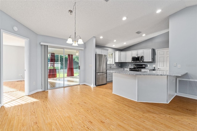 2557 Privada Dr, The Villages, FL 32162 - kitchen featuring stainless steel appliances, a chandelier, white cabinetry, a peninsula, and lofted ceiling