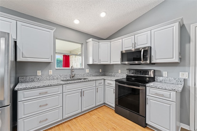 2557 Privada Dr, The Villages, FL 32162 - kitchen featuring stainless steel appliances, a sink, light wood-style flooring, a textured ceiling, and white cabinets