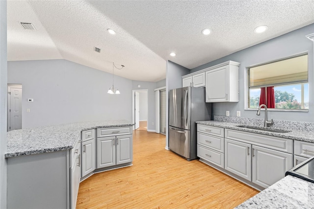 2557 Privada Dr, The Villages, FL 32162 - kitchen featuring freestanding refrigerator, a sink, light wood-type flooring, a textured ceiling, and decorative light fixtures