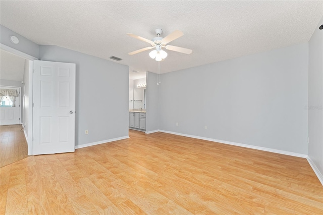2557 Privada Dr, The Villages, FL 32162 - unfurnished bedroom with light wood-style floors, a textured ceiling, baseboards, connected bathroom, and a ceiling fan