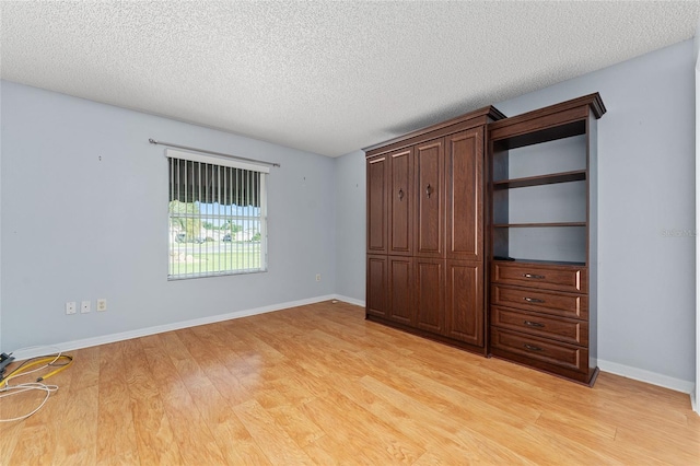 2557 Privada Dr, The Villages, FL 32162 - unfurnished bedroom featuring light wood-style flooring, a textured ceiling, and baseboards