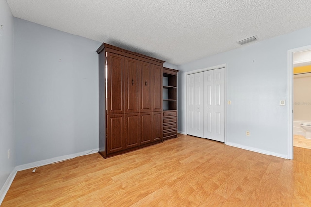 2557 Privada Dr, The Villages, FL 32162 - unfurnished bedroom with light wood-style floors, a closet, baseboards, and a textured ceiling