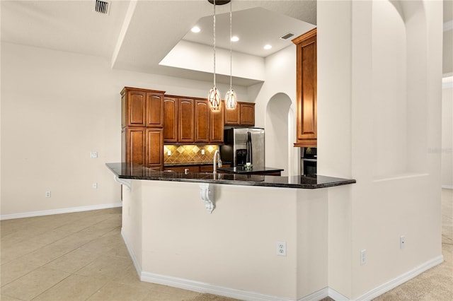 29152 David Ct, Tavares, FL 32778 - kitchen with stainless steel fridge, arched walkways, decorative backsplash, a peninsula, and a breakfast bar