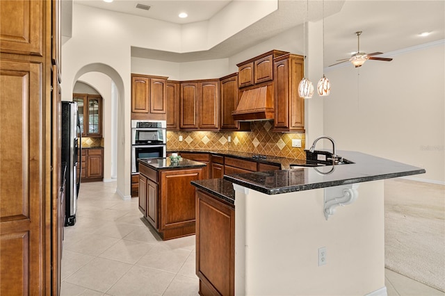 29152 David Ct, Tavares, FL 32778 - kitchen featuring custom range hood, appliances with stainless steel finishes, arched walkways, a peninsula, and a kitchen island