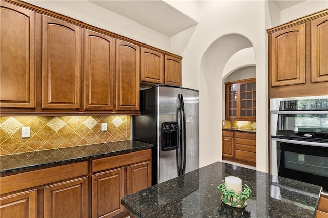 29152 David Ct, Tavares, FL 32778 - kitchen featuring appliances with stainless steel finishes, tasteful backsplash, dark stone countertops, and brown cabinetry