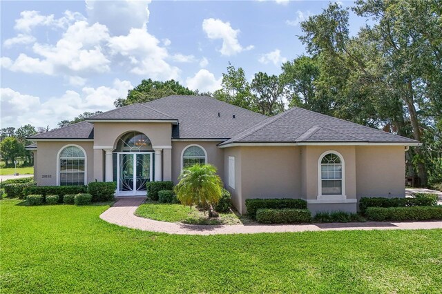 29152 David Ct, Tavares, FL 32778 - view of front of house with stucco siding, a front yard, and a shingled roof
