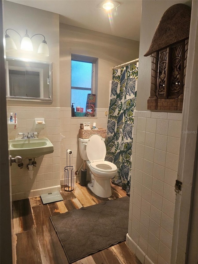 2433 Adams Ave, Deltona, FL 32738 - bathroom featuring tile walls, wood finished floors, a wainscoted wall, toilet, and a sink