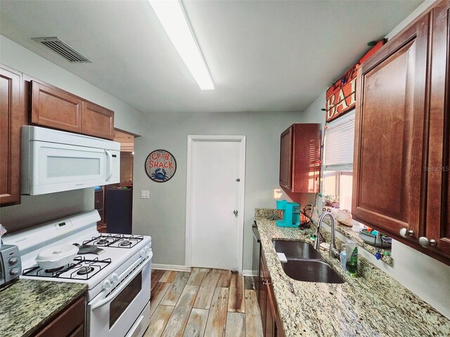 2433 Adams Ave, Deltona, FL 32738 - kitchen featuring white appliances, a sink, light wood-type flooring, baseboards, and light stone counters