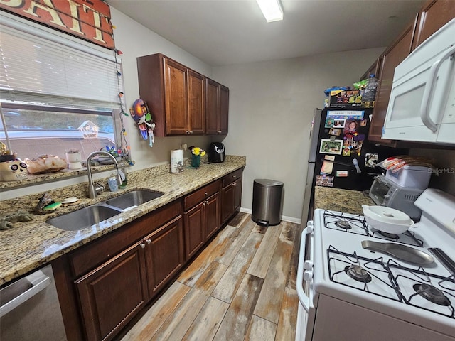 2433 Adams Ave, Deltona, FL 32738 - kitchen featuring appliances with stainless steel finishes, a sink, light wood-type flooring, light stone countertops, and baseboards