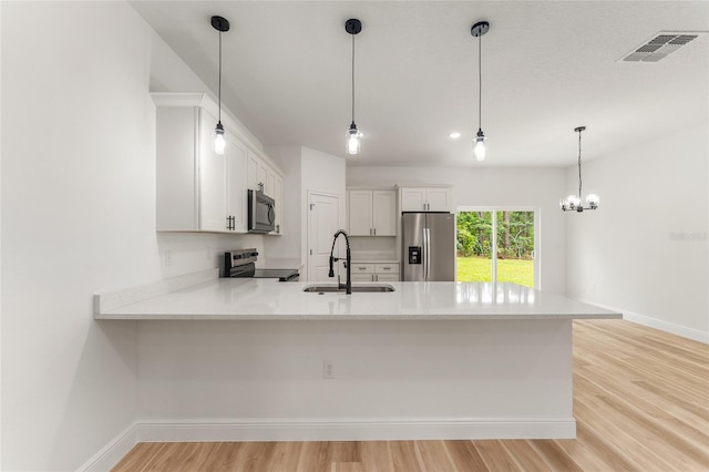 1809 W Linden Dr, Citrus Springs, FL 34434 - kitchen with stainless steel appliances, a peninsula, light wood-type flooring, light countertops, and white cabinetry