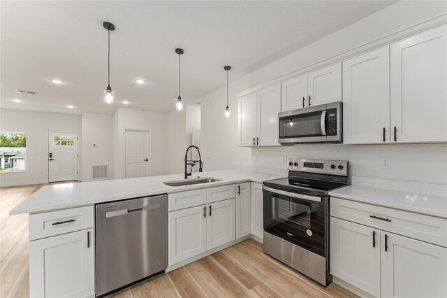 1809 W Linden Dr, Citrus Springs, FL 34434 - kitchen with stainless steel appliances, a peninsula, light wood-style floors, white cabinetry, and hanging light fixtures