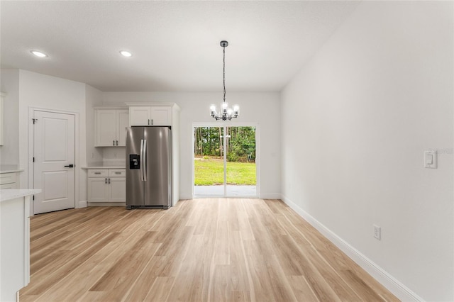 1809 W Linden Dr, Citrus Springs, FL 34434 - kitchen featuring stainless steel fridge, light countertops, light wood-style flooring, a chandelier, and white cabinetry