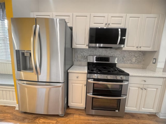 1180 Mesa Verde Ct, Clermont, FL 34711 - kitchen featuring stainless steel appliances, white cabinetry, light countertops, decorative backsplash, and wood finished floors