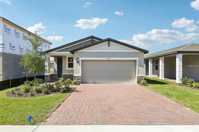 4973 Kaia Ave, Winter Haven, FL 33884 - view of front of home with stone siding, a garage, decorative driveway, and a front lawn