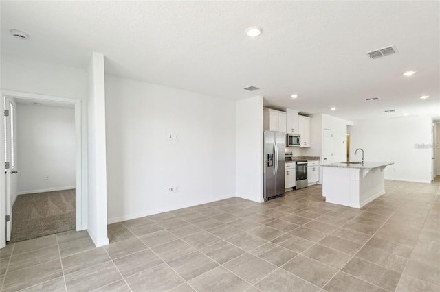 4973 Kaia Ave, Winter Haven, FL 33884 - kitchen with stainless steel appliances, a sink, recessed lighting, white cabinetry, and a center island with sink