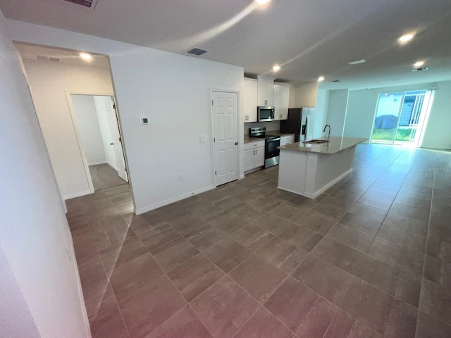 4957 Kaia Ave, Winter Haven, FL 33884 - kitchen with stainless steel appliances, white cabinetry, an island with sink, a sink, and open floor plan