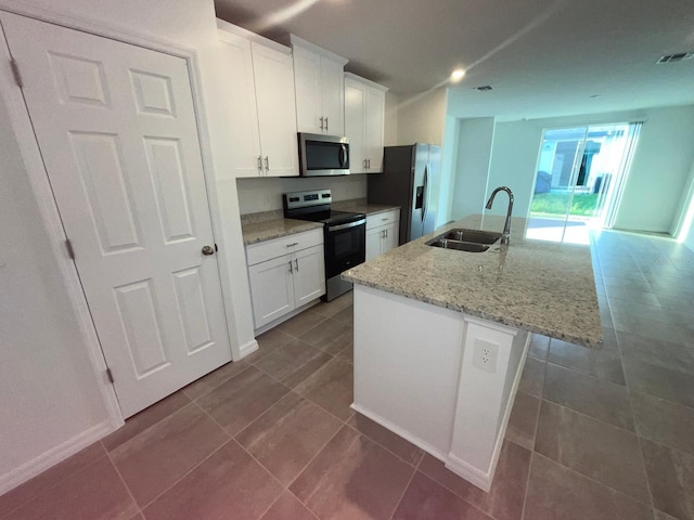4957 Kaia Ave, Winter Haven, FL 33884 - kitchen featuring appliances with stainless steel finishes, a sink, white cabinets, and a center island with sink