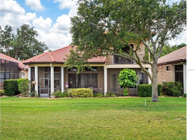 9335 San Jose Blvd, Howey In The Hills, FL 34737 - back of house featuring a sunroom, a tile roof, a yard, and stucco siding