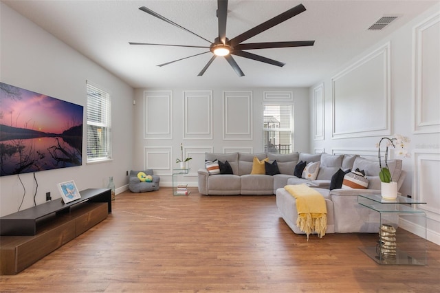 637 Neptune Dr, Groveland, FL 34736 - living room with wood finished floors, a ceiling fan, and a decorative wall