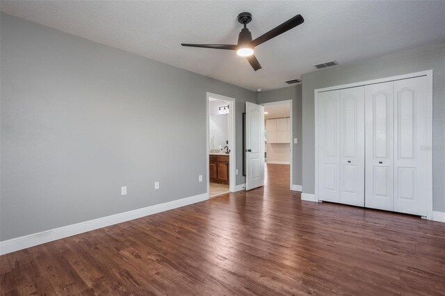637 Neptune Dr, Groveland, FL 34736 - unfurnished bedroom with wood finished floors, baseboards, a closet, a ceiling fan, and ensuite bathroom