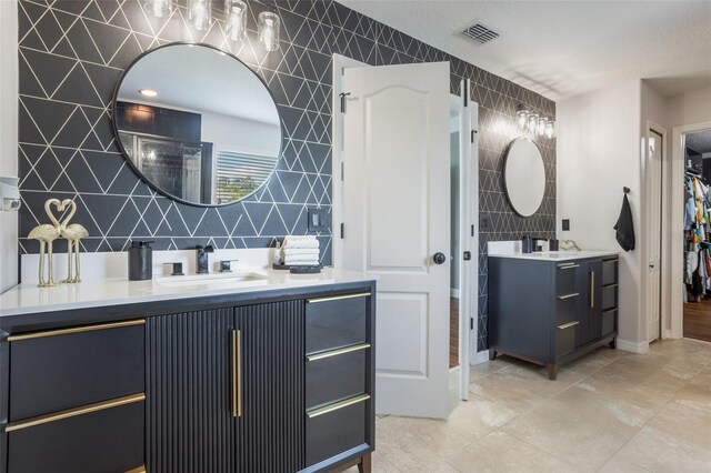 637 Neptune Dr, Groveland, FL 34736 - full bathroom with two vanities, tile walls, baseboards, and a walk in closet