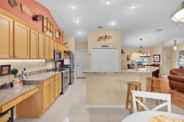 17355 SE 110th Ter, Summerfield, FL 34491 - kitchen featuring stainless steel appliances, a kitchen bar, a kitchen island, decorative light fixtures, and light stone countertops