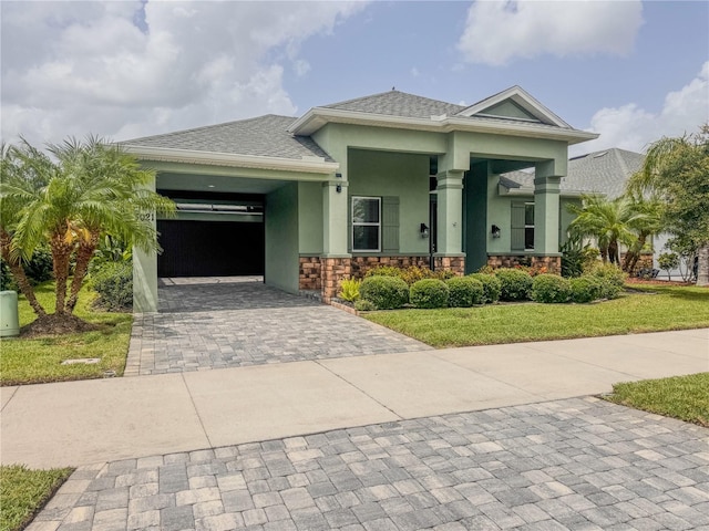 3021 King Palm Dr, New Smyrna Beach, FL 32168 - prairie-style house featuring decorative driveway, an attached garage, stucco siding, a front yard, and stone siding