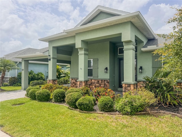 3021 King Palm Dr, New Smyrna Beach, FL 32168 - view of front of property with stucco siding, stone siding, a front yard, and a porch