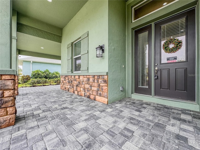 3021 King Palm Dr, New Smyrna Beach, FL 32168 - view of exterior entry with covered porch, stone siding, and stucco siding
