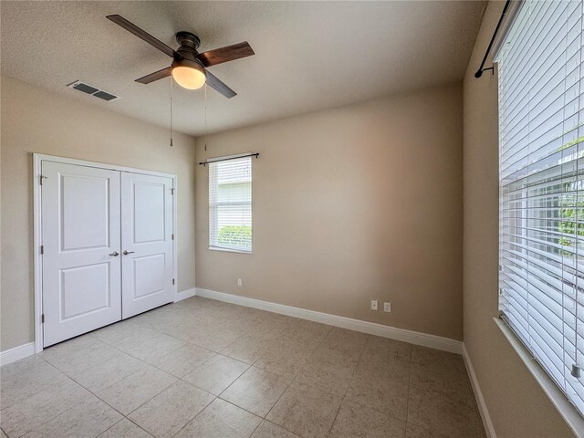 3021 King Palm Dr, New Smyrna Beach, FL 32168 - unfurnished bedroom with light tile patterned flooring, ceiling fan, and a closet