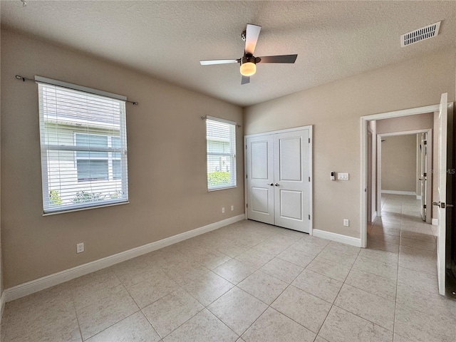3021 King Palm Dr, New Smyrna Beach, FL 32168 - unfurnished bedroom with a textured ceiling, light tile patterned floors, ceiling fan, and a closet