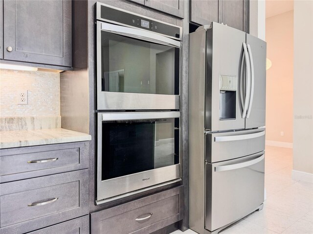 3021 King Palm Dr, New Smyrna Beach, FL 32168 - kitchen with stainless steel appliances, tasteful backsplash, light tile patterned floors, gray cabinetry, and light stone counters
