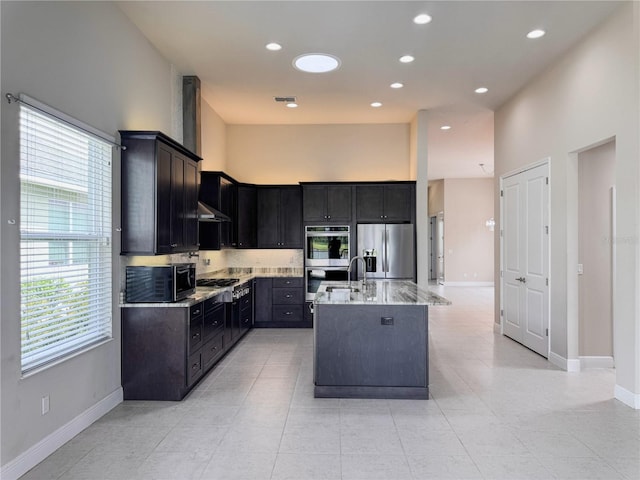 3021 King Palm Dr, New Smyrna Beach, FL 32168 - kitchen with stainless steel appliances, a towering ceiling, light stone counters, under cabinet range hood, and a center island with sink