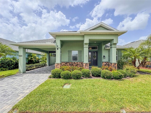 3021 King Palm Dr, New Smyrna Beach, FL 32168 - view of front facade featuring stucco siding, decorative driveway, stone siding, a front lawn, and a carport