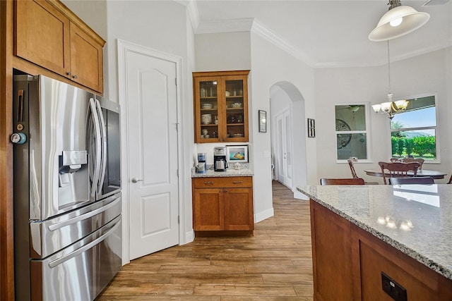 6008 Apex Way, Lady Lake, FL 32159 - kitchen with stainless steel fridge, arched walkways, brown cabinetry, a chandelier, and wood finished floors