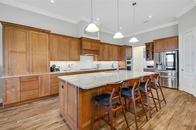 6008 Apex Way, Lady Lake, FL 32159 - kitchen featuring stainless steel appliances, brown cabinets, backsplash, a center island with sink, and a kitchen bar