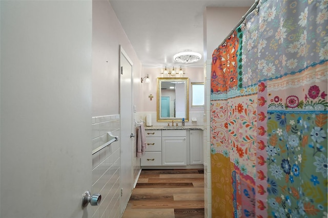 27212 Orange Ave, Yalaha, FL 34797 - bathroom featuring tile walls, vanity, wood finished floors, and wainscoting