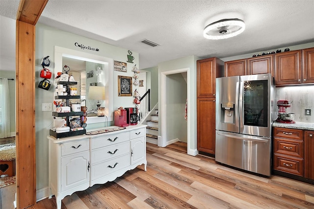 27212 Orange Ave, Yalaha, FL 34797 - kitchen featuring stainless steel refrigerator with ice dispenser, light wood-style flooring, a textured ceiling, brown cabinets, and white cabinets