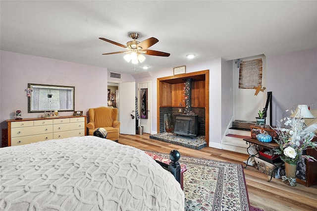 27212 Orange Ave, Yalaha, FL 34797 - bedroom with light wood-style floors, a wood stove, and a ceiling fan