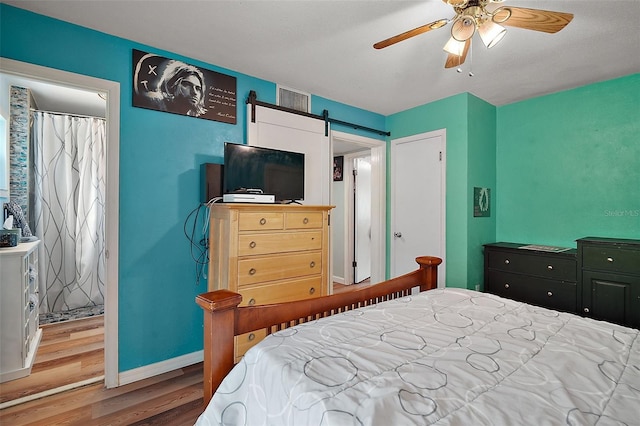 27212 Orange Ave, Yalaha, FL 34797 - bedroom with wood finished floors, a barn door, and ceiling fan